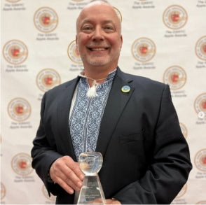 Jason posing with another award, clear award and dressed in a suit