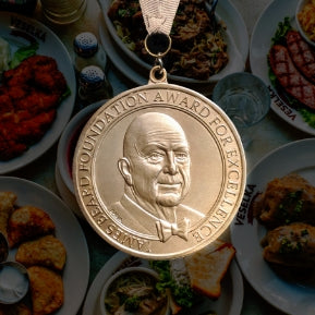 Games beard award medal on a background containing dishes of Veselka's food 