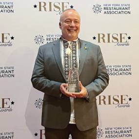 Jason in a suit, holding RISE award