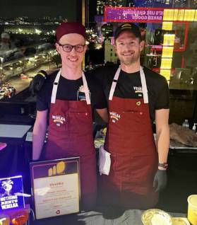 Vitalii and Justin working a catering event in Veselka aprons smiling 