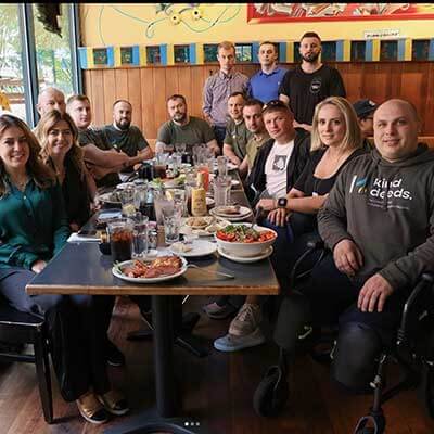 Ukrainian soilders gathered around a dining room table at Veselka 2nd ave, Vitalii and other Ukrainian workers gathered in the background 