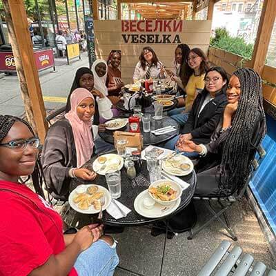 Mixed race group of people posing and eating in Veselka's outdoor dining section. 